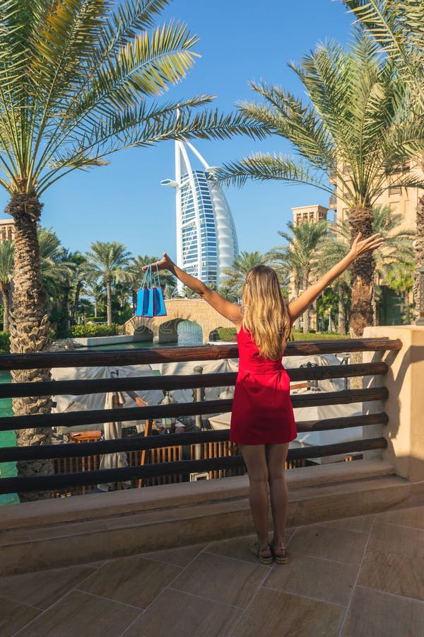 Burjal Arabier van Madinat Jumeirah door jonge toeristenvrouw wordt gezien kleedde zich in rode kleding die stock fotografie Burjal Arabier van Madinat Jumeirah door jonge toeristenvrouw wordt gezien kleedde zich in rode kleding die stock fotografie