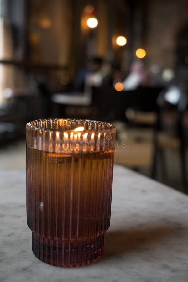 Burning Candle in Brown Glass Jar on the Marble Table. Stock Photo