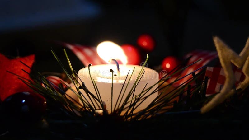 Burning candle and Christmas decoration over snow and wooden background, elegant shot with festive mood