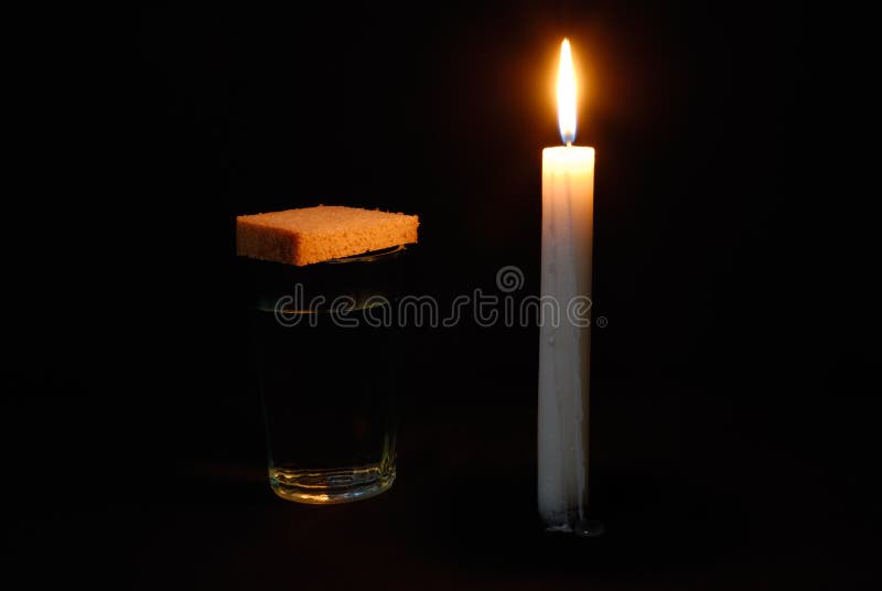 Burning candle, a glass with water and breads