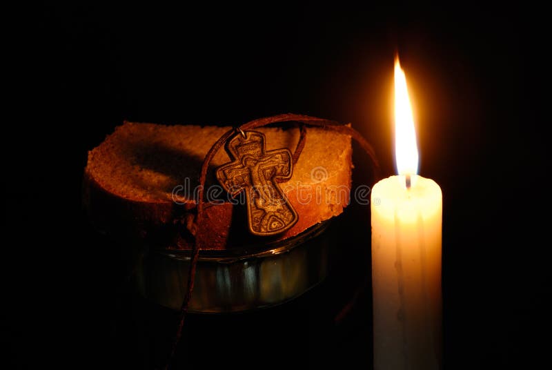 Burning candle, rood, glass with water and breads