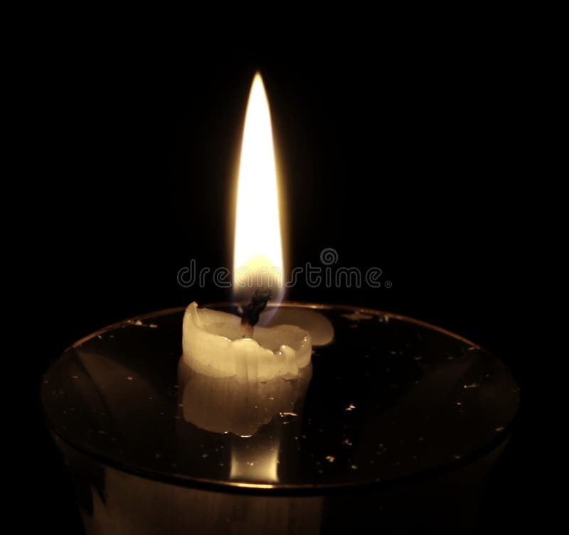 A Burning Candle Set in a Glass Filled with Clear Liquid Stock Photo