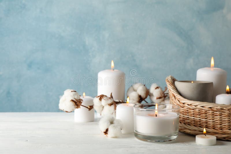 Burning candles, basket and cotton on wooden table, space for text royalty free stock photography
