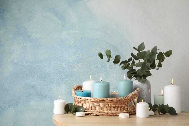 Burning candles, basket and vase with eucalyptus against blue background royalty free stock image