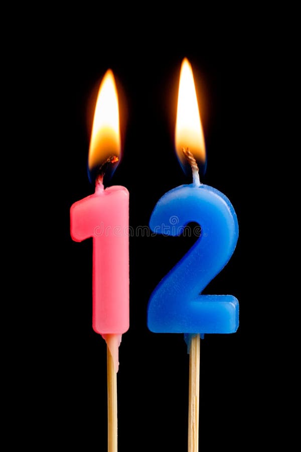 Burning candles in the form of 12 twelve figures numbers, dates for cake isolated on black background. The concept of celebratin