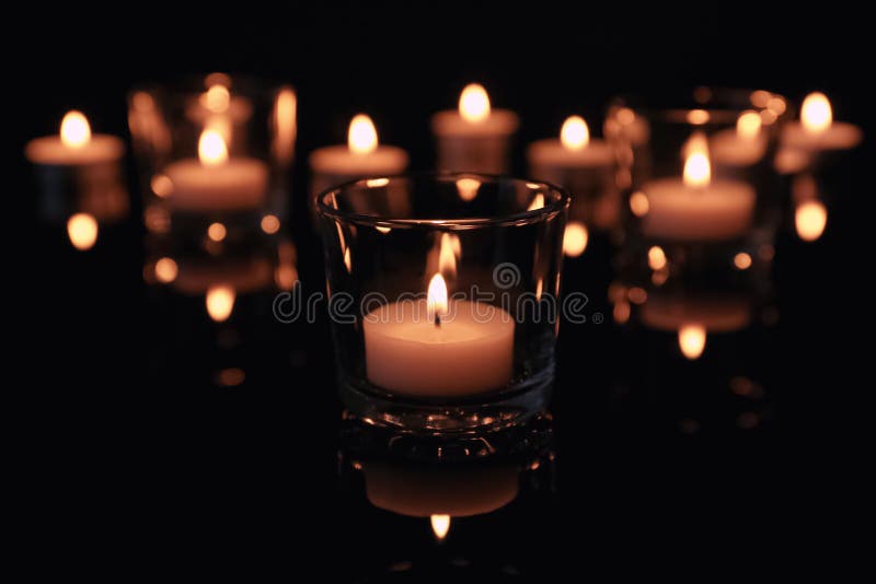 Burning candles in glass holders on dark background