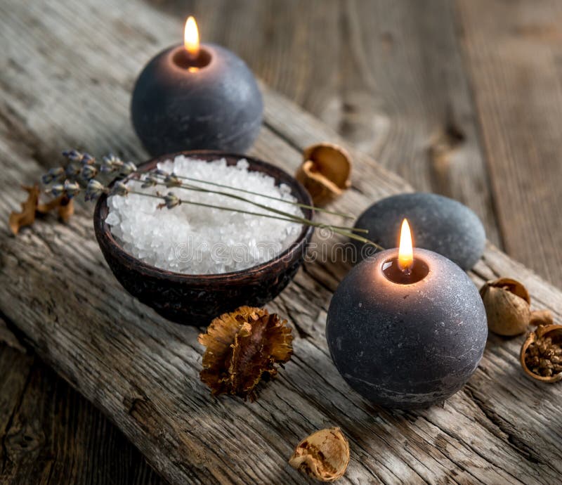 Burning candles and sea salt on wooden background.