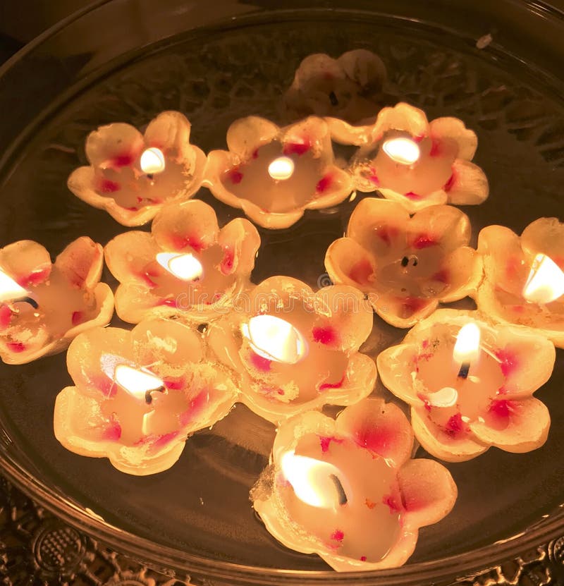 Burning Candles in the Shape of a Flower are Floating in the Water