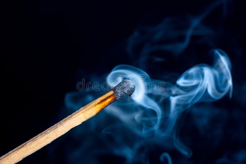 Burning match on black background with smoke clouds. Macro photo.