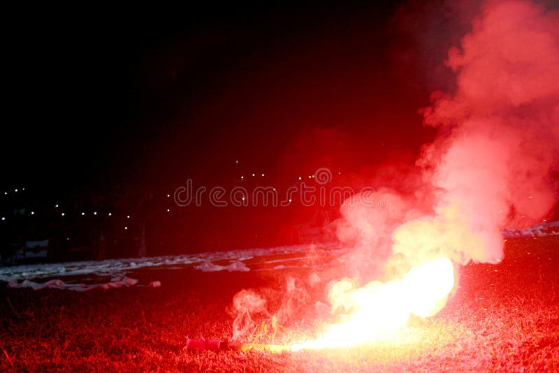 Burning red flare, flame, football hooligan. football fans lit up the lights and smoke bombs on the football pitch. Burning red fl stock image Burning red flare, flame, football hooligan. football fans lit up the lights and smoke bombs on the football pitch. Burning red fl stock image