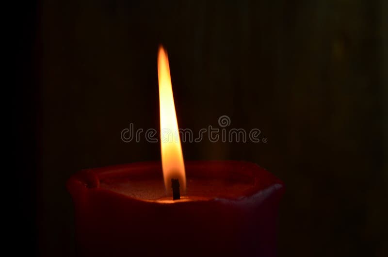 Burning Single Red Candle with Dancing Flame on the Dark Background