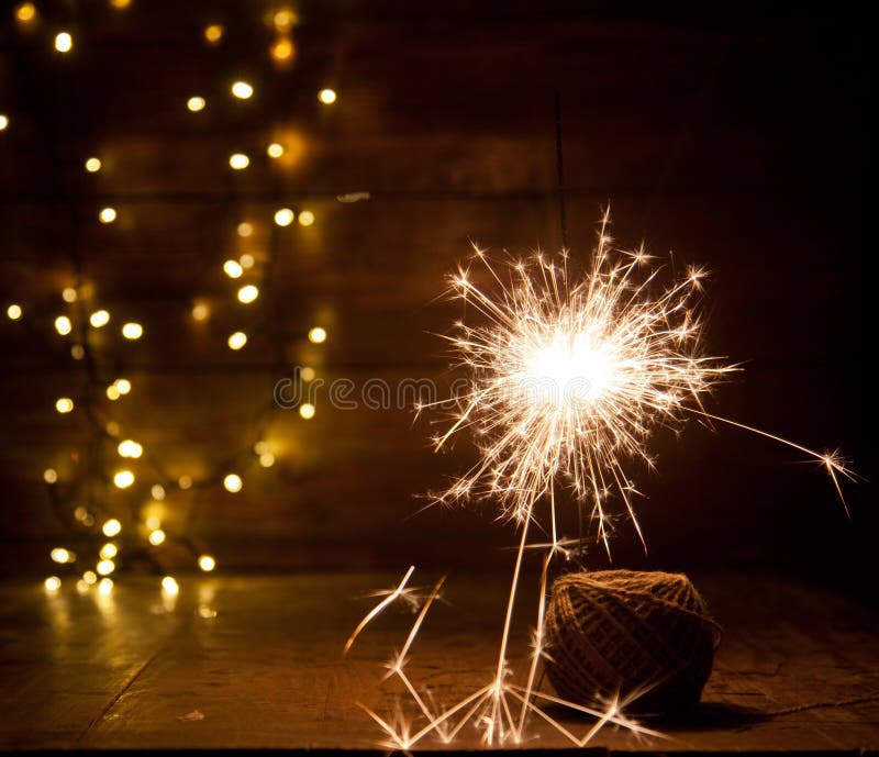 Burning Sparkler and Christmas Lights on Wooden Background Stock Image