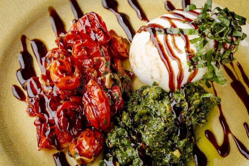 Burrata ost med Nutless Pesto och grillade tomater royaltyfri bild Burrata ost med Nutless Pesto och grillade tomater royaltyfri bild