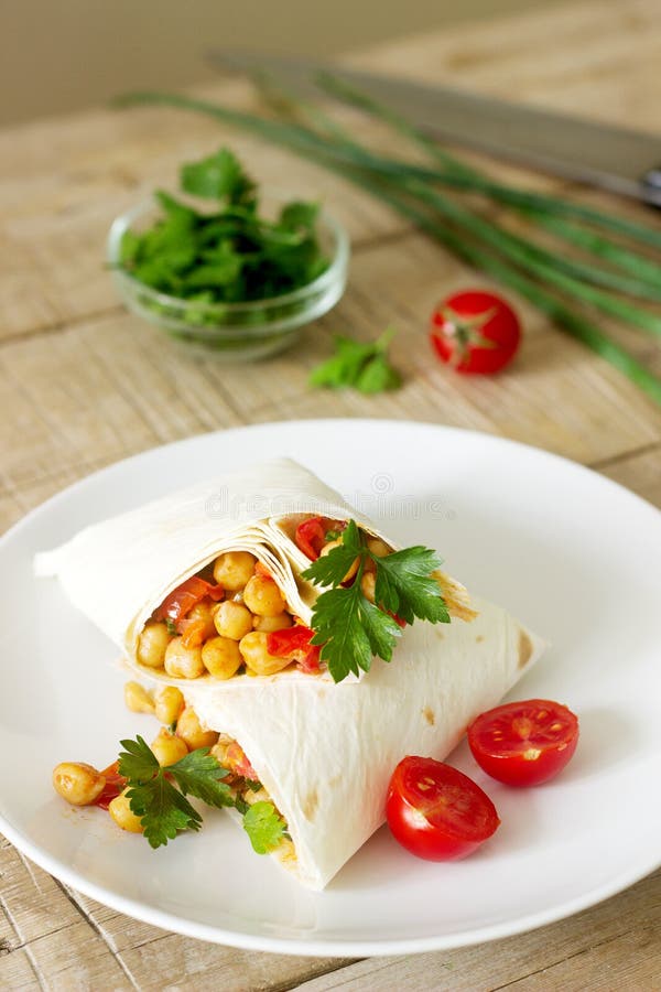 Burrito lub shawurma z chickpeas, pomidorami i pietruszką na, zaświecamy talerza obraz stock Burrito lub shawurma z chickpeas, pomidorami i pietruszką na, zaświecamy talerza obraz stock