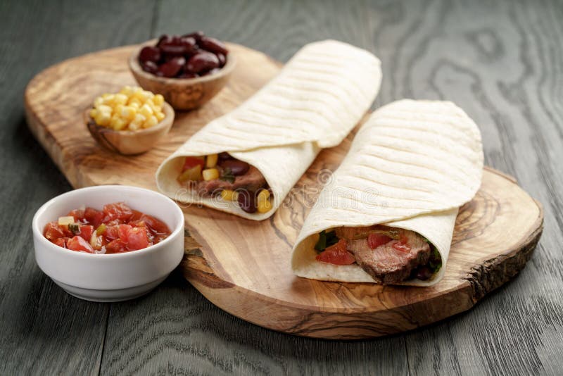 Burritos with Beef Steak, Corn, Black Beans and Salsa Sauce on Cutting