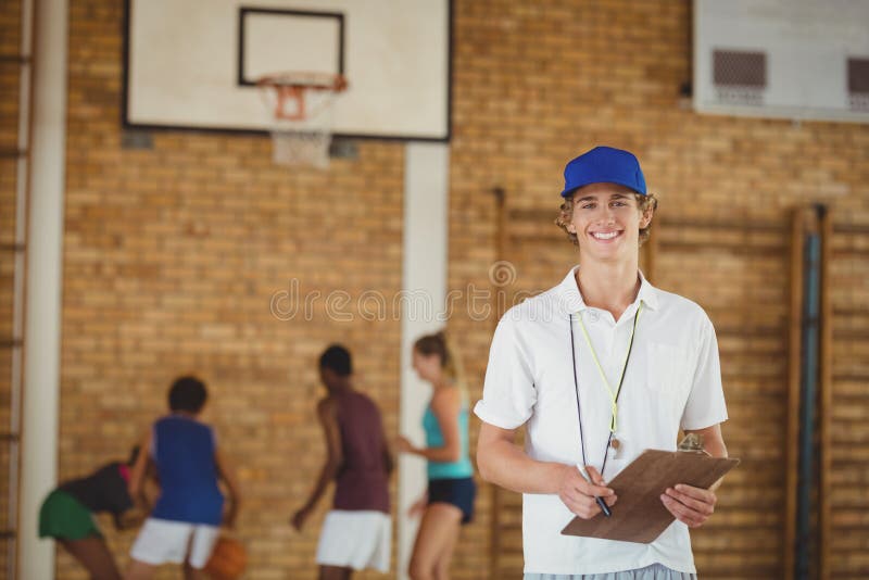 Bus die bij camera glimlachen terwijl het speelbasketbal van het middelbare schoolteam op achtergrond royalty-vrije stock fotografie Bus die bij camera glimlachen terwijl het speelbasketbal van het middelbare schoolteam op achtergrond royalty-vrije stock fotografie