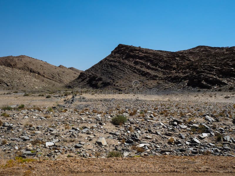 Rough rock mountain drought landscape ground of Namib desert unique geography with splitting stone, desert green plant and clear blue sky background, Namibia. Rough rock mountain drought landscape ground of Namib desert unique geography with splitting stone, desert green plant and clear blue sky background, Namibia