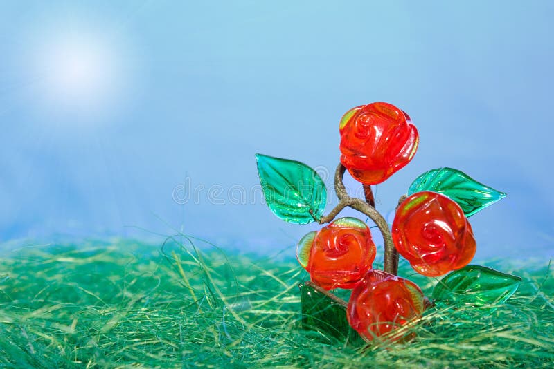 Grow to the sun: glass tree (rose bush) in artificial grass on blue background. Grow to the sun: glass tree (rose bush) in artificial grass on blue background.