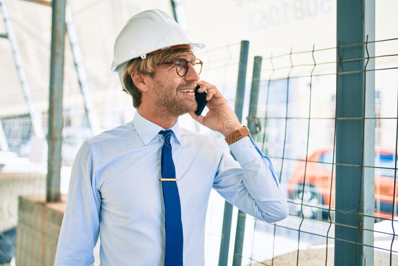 Business architect man wearing hardhat standing outdoors of a building project speaking on the phone stock photos