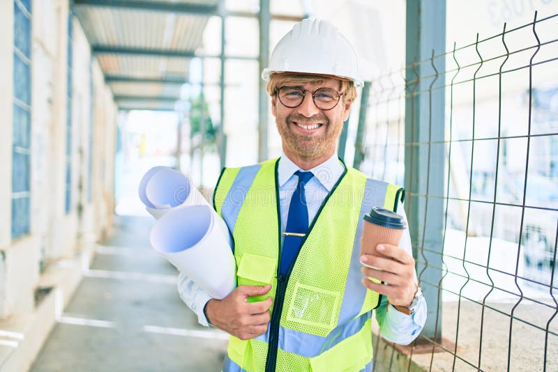 Business architect man wearing hardhat standing outdoors of a building project wearing reflective vest drinking a cup of coffee royalty free stock photos
