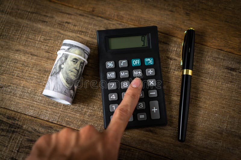 Business concept with a calculator and a roll of dollar banknote stock photography
