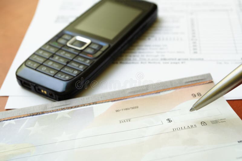 Blank check, pen and mobile phone on a desk as a business concept. Blank check, pen and mobile phone on a desk as a business concept