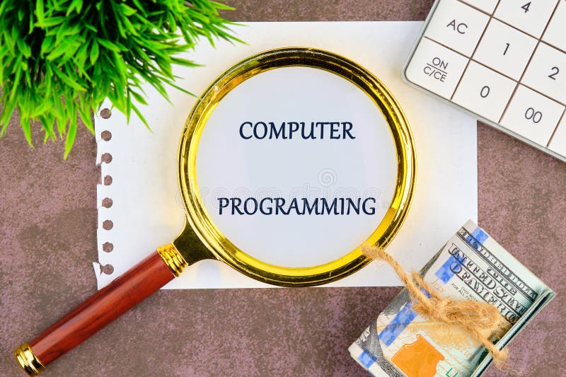 Business concept. Words COMPUTER PROGRAMMING through a magnifying glass on a white sheet of notepad stock photo