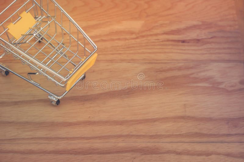 Business and Financial Concept : Top view of yellow mini shopping cart or supermarket trolley setting on wooden floor. stock photo Business and Financial Concept : Top view of yellow mini shopping cart or supermarket trolley setting on wooden floor. stock photo