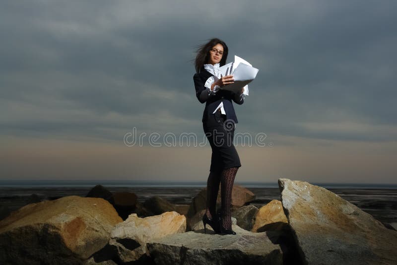 Business ladies standing on rocks by the sea, agai