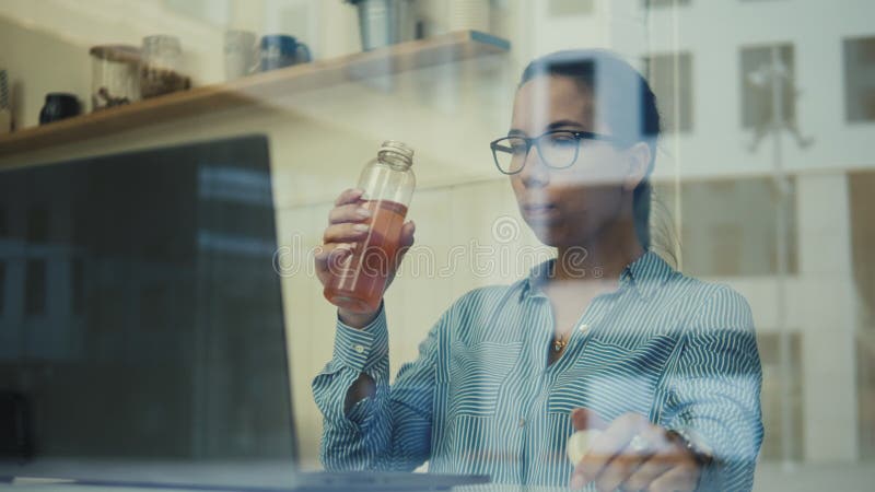 Business lady working on a laptop is filmed through the window stock video footage