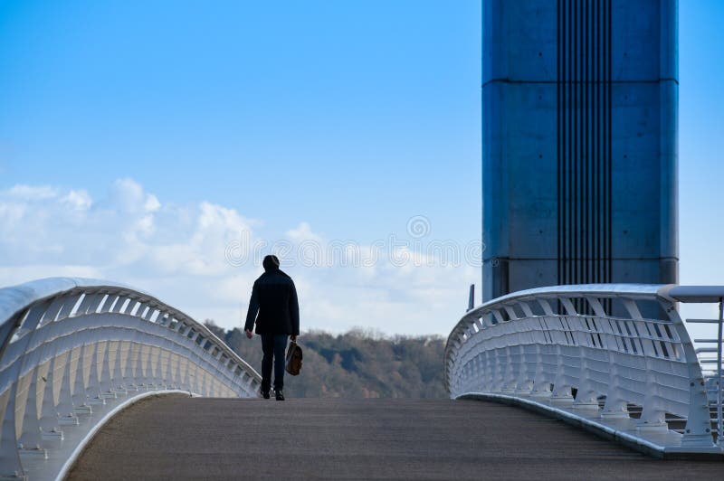 Business man with suitcase walking on a bridge.