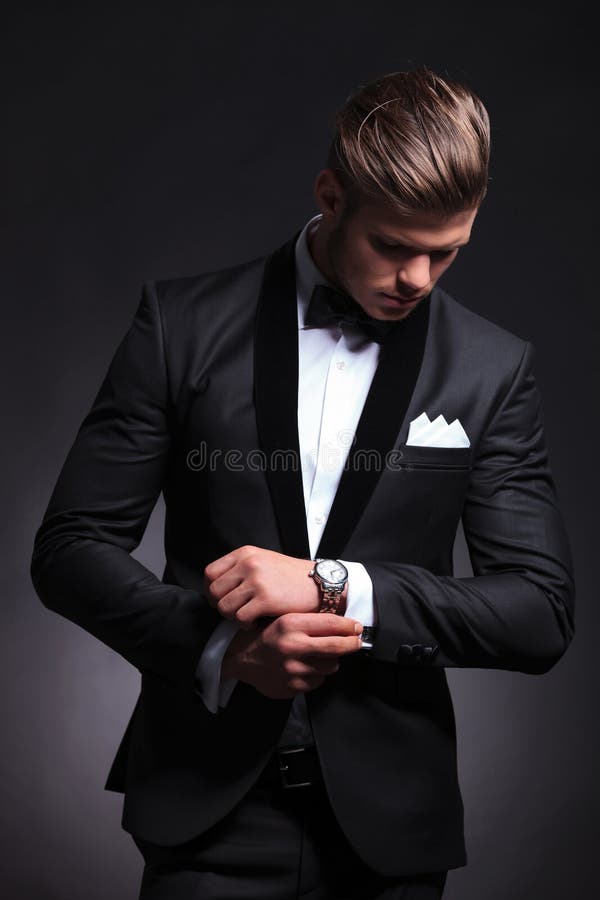 Business man fixes and looks at cufflinks royalty free stock photo