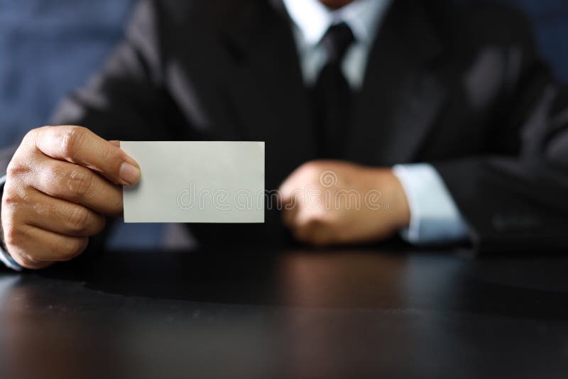 Business man hands in black suit sitting and showing or giving blank business name card while sitting in meeting room