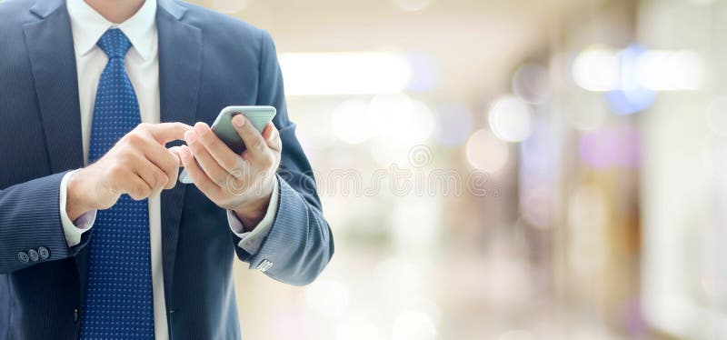 Business man hands using smart phone over blur office with copy