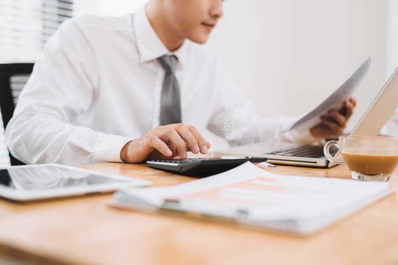 Business man holding paper, busy working on laptop computer and using calculate in modern office, close up. Work process concept stock photography Business man holding paper, busy working on laptop computer and using calculate in modern office, close up. Work process concept stock photography