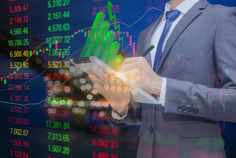 Business man holding tablet with green stick graph on top and background is oil and gas processing platform and stock index graph. stock photography