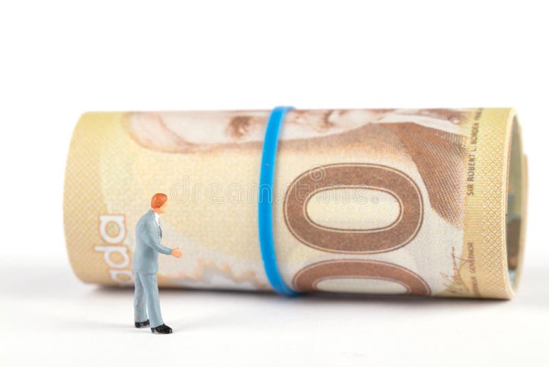 Business man looking at a roll of Canadian dollar banknotes in a daze.