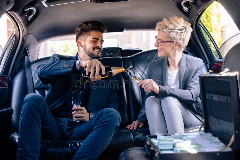 Business man pours champagne to business woman