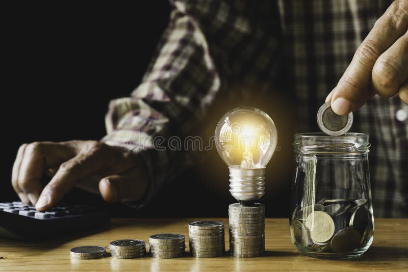 Business man putting coin with light bulb on table for saving bank and account for his money all in finance accounting concept stock photo Business man putting coin with light bulb on table for saving bank and account for his money all in finance accounting concept stock photo