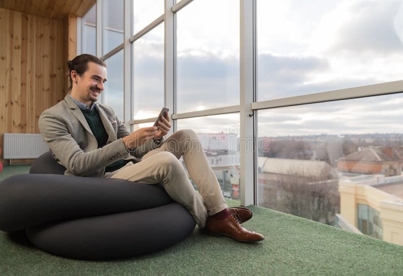 Business Man Using Cell Smart Phone Sit in front Panoramic Window Businessman In Coworking Center