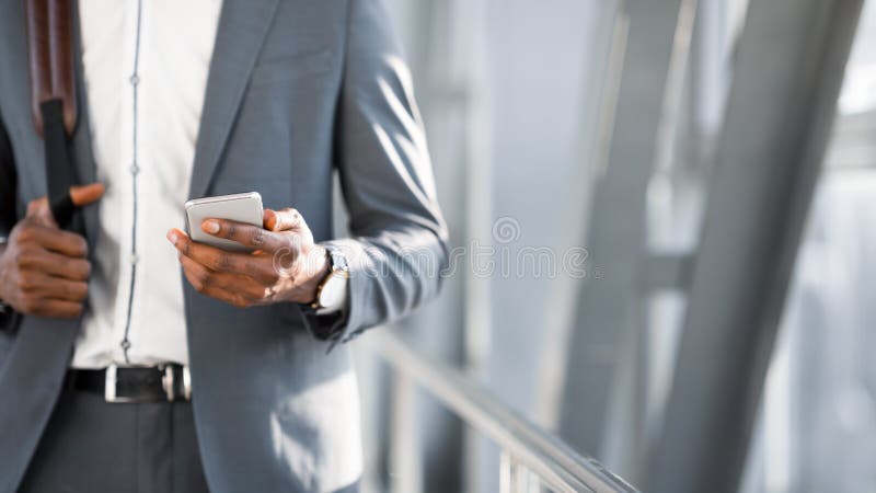 Travel App. Unrecognizable Black Business Man Using Phone Walking To Gate In Airport Indoors. Cropped, Free Space, Panorama. Travel App. Unrecognizable Black Business Man Using Phone Walking To Gate In Airport Indoors. Cropped, Free Space, Panorama