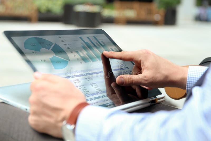 Business man working and analyzing financial figures on a graphs on a laptop outside stock images Business man working and analyzing financial figures on a graphs on a laptop outside stock images
