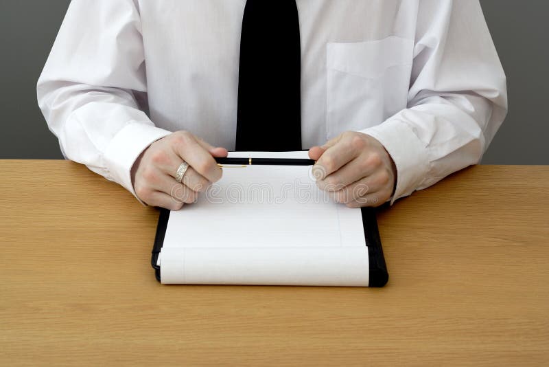 Man in shirt and tie sat at a table for a business meeting, holding a pen. Man in shirt and tie sat at a table for a business meeting, holding a pen