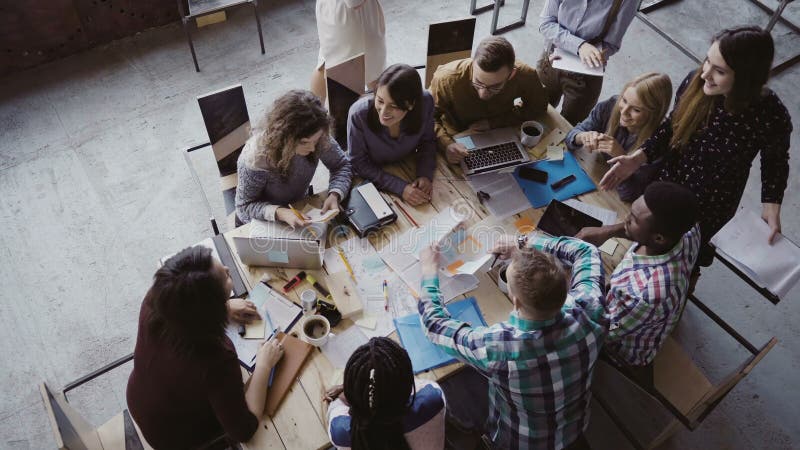 Business meeting at loft shared space. Multiethnic team talking, woman manager giving direction to people. Top view. royalty free stock photo Business meeting at loft shared space. Multiethnic team talking, woman manager giving direction to people. Top view. royalty free stock photo
