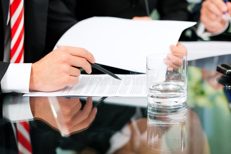 Business - meeting in an office; lawyers or attorneys (only hands) discussing a document or contract agreement. Business - meeting in an office; lawyers or attorneys (only hands) discussing a document or contract agreement