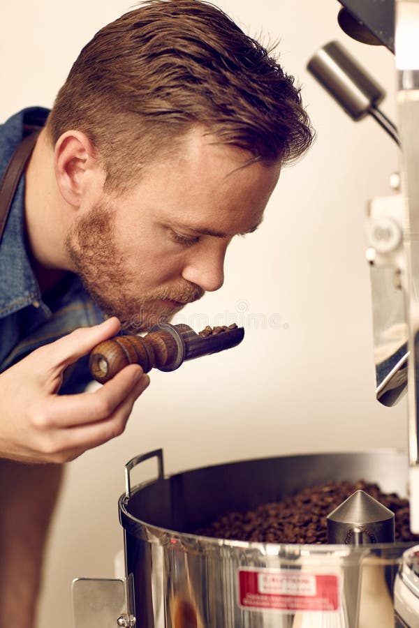 Business owner smelling freshly roasted coffee beans for aromati