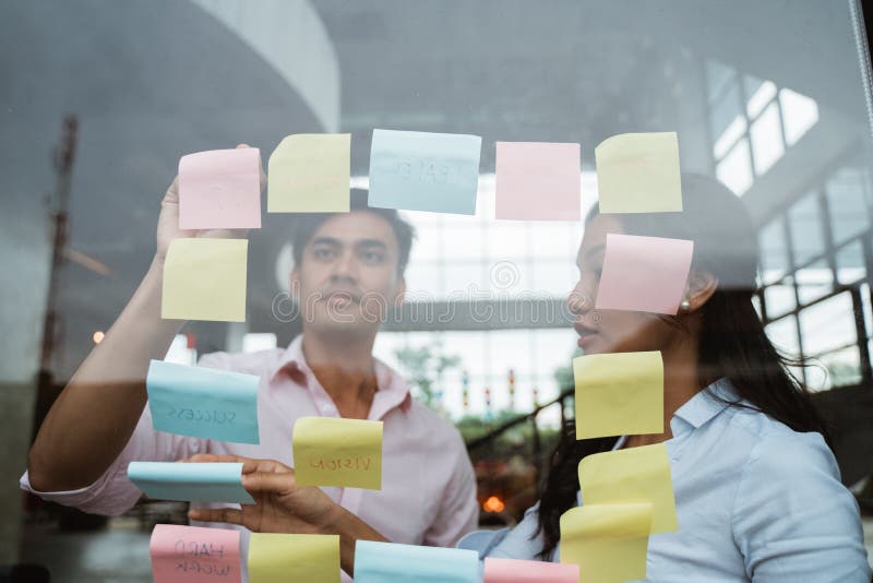 Business partner brainstorming by sticking idea into the glass window royalty free stock photos Business partner brainstorming by sticking idea into the glass window royalty free stock photos