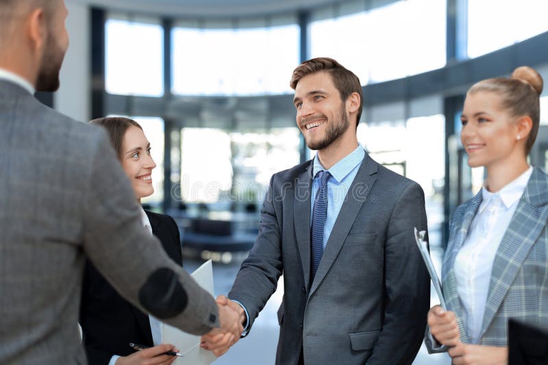 Business partners handshaking over business objects on workplace. stock photos