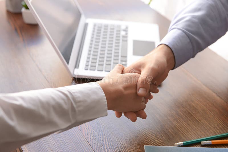 Business partners shaking hands at table in office. Business partners shaking hands at table in office