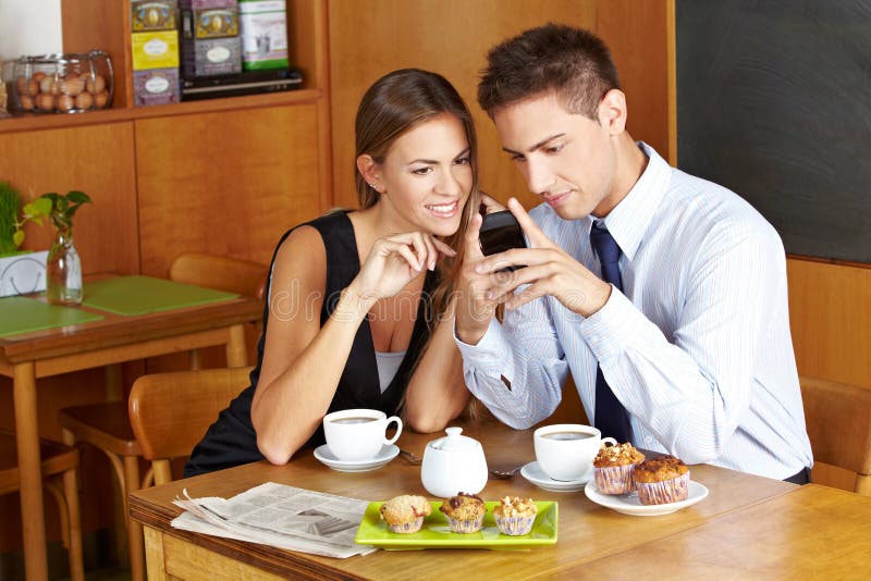 Business people in cafÃ© with smartphone having a meeting